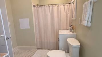 A bathroom with a toilet, sink, shower curtain, and a patterned floor.