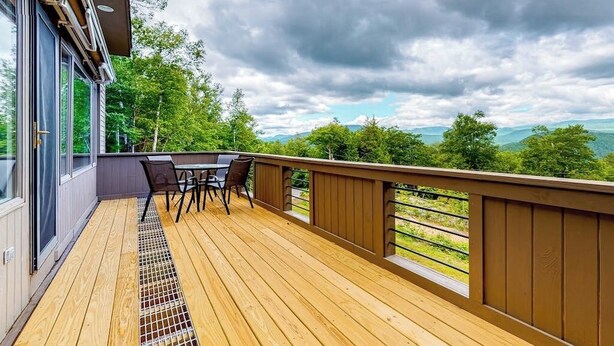 A wooden deck with a table and chairs, overlooking a mountainous landscape. - Mountain view retreat with fast WiFi, washer/dryer, & central AC (Jackson)