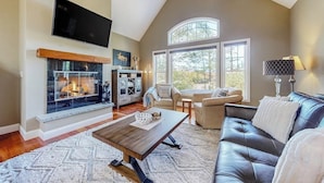 A living room with a fireplace, a television, and a large window. - Lovely home with water view, hot tub, fireplace, & washer/dryer (Conway)