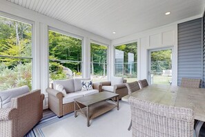 A sunroom with large windows, wicker furniture, and a view of greenery. - Stunning Mountain View Home: In the heart of outdoor entertainment (Bartlett)