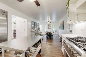 Una cocina moderna con una isla central, electrodomésticos de acero inoxidable y un comedor con mesa y sillas.