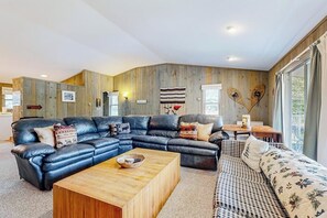 Ein modernes Wohnzimmer mit einem Ecksofa, einem Holztisch und einem gemusterten Sofa.