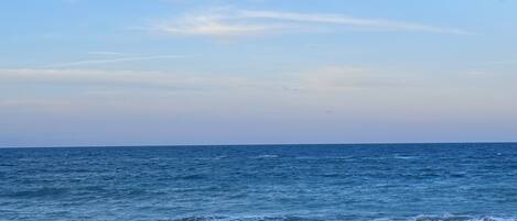 A beach with waves, a clear sky, and a distant horizon.
