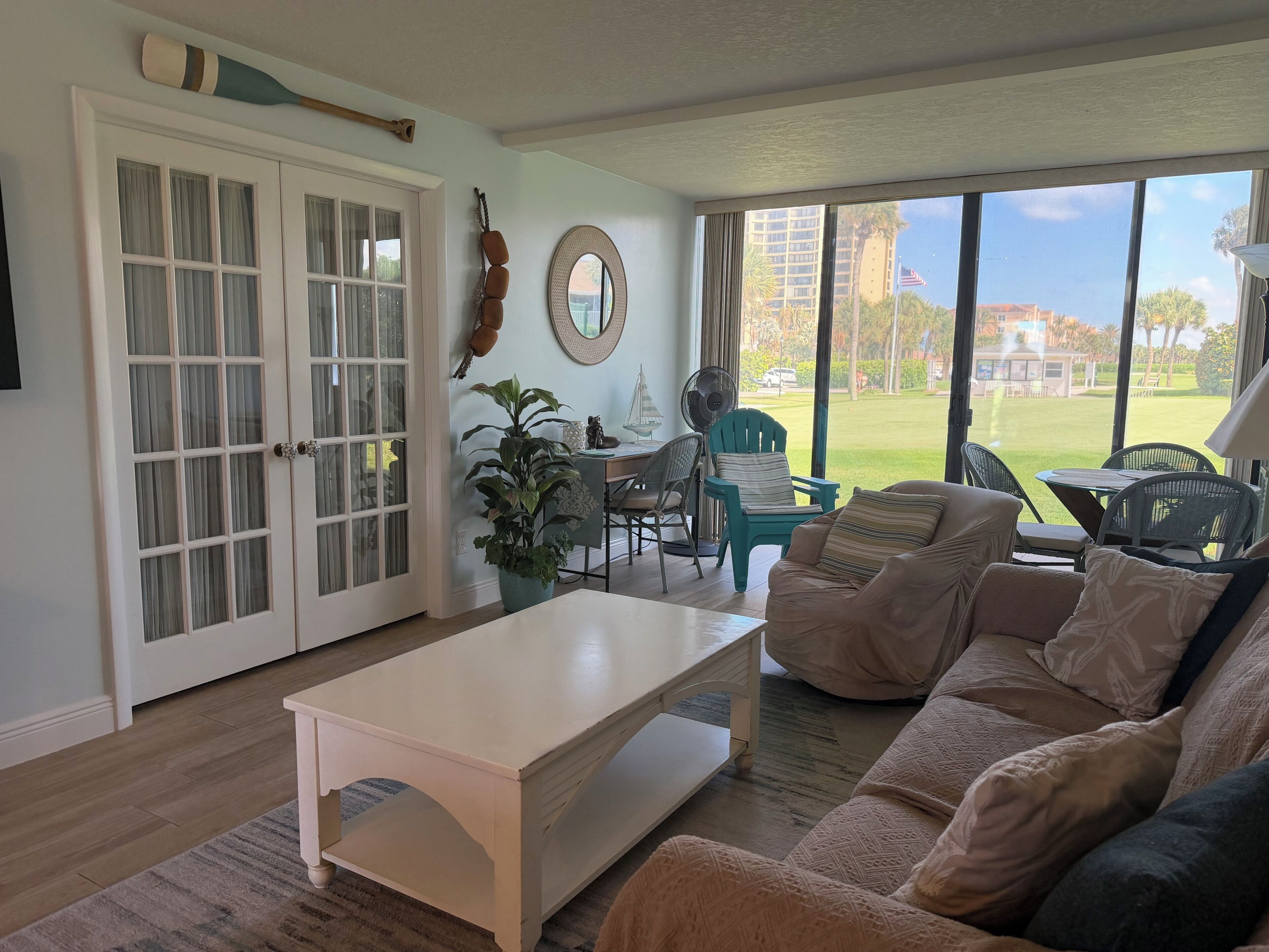 A living room with a white coffee table, beige sofa, and a dining area with chairs and a table.