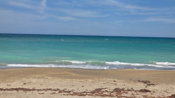 Ein Strand mit klarem türkisblauem Wasser und einem sandigen Ufer.