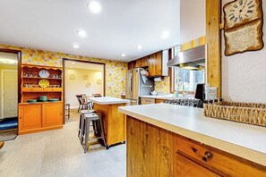 A kitchen with wooden cabinets, a central island, and a clock on the wall.