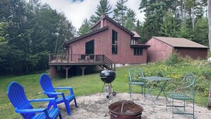 Eine rustikale Holzhütte mit einer Veranda, Sitzgelegenheiten im Freien und einem Grill.