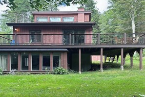 A two-story wooden house with a balcony, large windows, and a covered outdoor area. - MCM hideaway with entertainer's deck, dog-friendly yard, Ping-Pong & WFH desks (Franconia)
