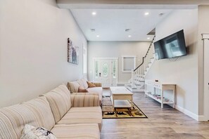 Ein Wohnzimmer mit einer Couch, einem Couchtisch und einem an der Wand befestigten Fernseher.