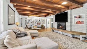 A living room with a fireplace, a sofa, a television, and a bookshelf.