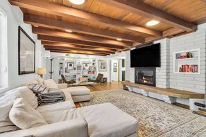 Ein Wohnzimmer mit Kamin, Sofa, Fernseher und Bücherregal.