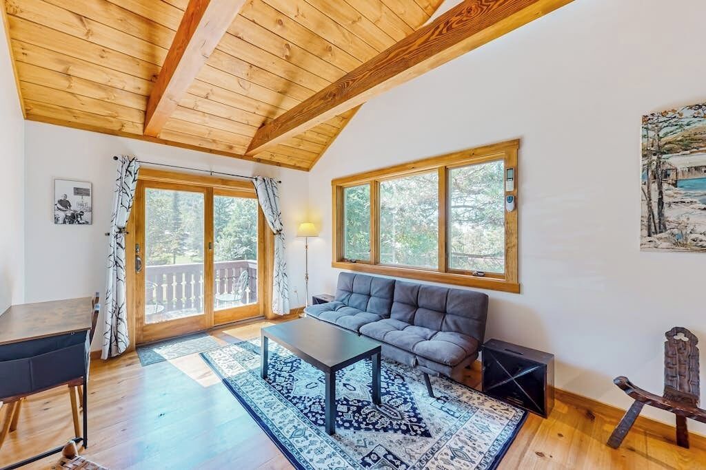 Une pièce avec un plafond en bois, un canapé, une table et une grande fenêtre.