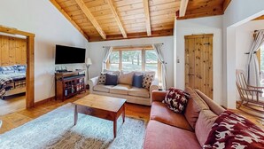 A cozy living room with a wooden ceiling, a sofa, a coffee table, and a television. - Mittersill Village Gem  | House in Franconia with balcony, fireplace, & dogs ok (Franconia)