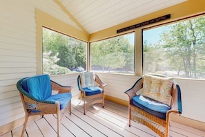 A covered porch with wicker furniture and large windows. - Mountain view condo with gas fireplace, balcony, & grill - close to skiing (Jackson)