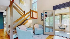 Uma sala de estar espaçosa com escada de madeira, porta de vidro para o exterior e um espaço de estar aconchegante.
