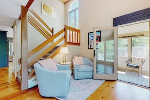 A spacious living room with a wooden staircase, a glass door leading outside, and a cozy seating area. - Mountain view condo with gas fireplace, balcony, & grill - close to skiing (Jackson)