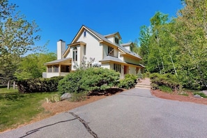 A two-story house with a front porch, a chimney, and a driveway leading to the entrance. - Mountain view condo with gas fireplace, balcony, & grill - close to skiing (Jackson)