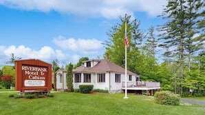 A Riverbank Motel & Cabins with a large sign, a single-story building, and a flagpole. - Charming and casual motel in a great location with shared resort amenities (Lincoln)