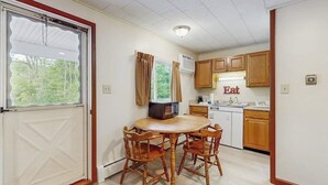 A compact kitchen with a dining table and chairs, a microwave, and wooden cabinets. - Charming and casual motel in a great location with shared resort amenities (Lincoln)