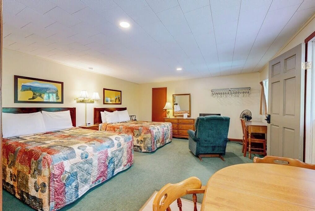 Hotelkamer met twee bedden, een bureau, een stoel, een eettafel en een spiegel.
