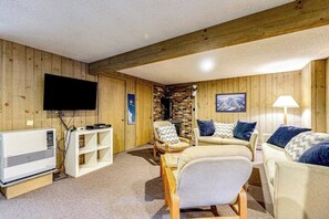 Ein Zimmer mit Holzwänden, einem Kamin, einem Flachbildfernseher, einer Couch und einer Lampe.