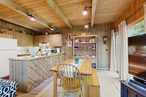 Ein gemütliches Blockhaus-Interieur mit einer Holztischlerei, einer Küche und einem Fernseher.