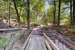A wooden boardwalk leading through a forested area with trees and rocks. - Central condo with Ping-Pong, outdoor pool, tennis, deck, & wood fireplace (Conway)