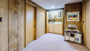 Ein Korridor mit Holzwänden, ein Küchenbereich mit Mikrowelle und Herd, und eine Tür zu einem weiteren Raum.