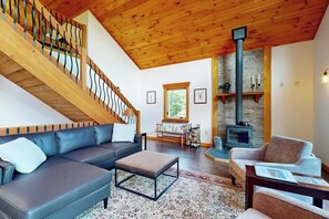 Ein modernes Wohnzimmer mit einer Holztreppe, einem Kamin und einem Sofa.