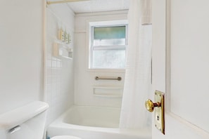 Un baño con bañera, inodoro y ventana.