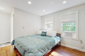 A bedroom with a bed, a window with blinds, and a door.