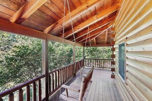 Una cabaña de madera con porche, ventanas amplias y vistas al bosque.