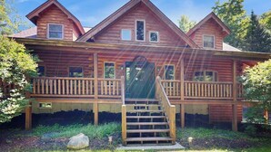 Eine Holzhütte mit Veranda, Treppe und großem Fenster.