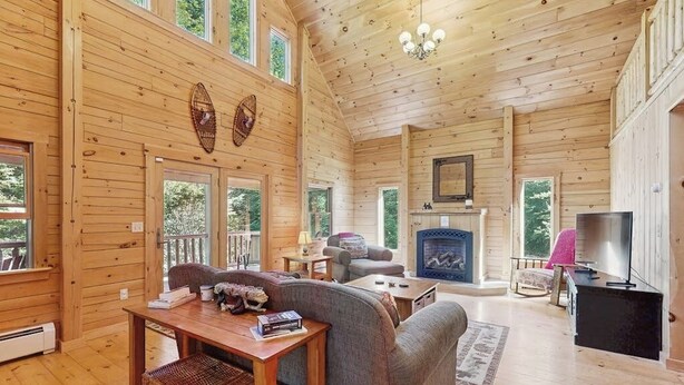 Ein Holzblockhaus-Interieur mit Kamin, Sofa und Fernseher.