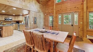 Ein Holzblockhaus-Interieur mit Essbereich, Küche und großen Fenstern.