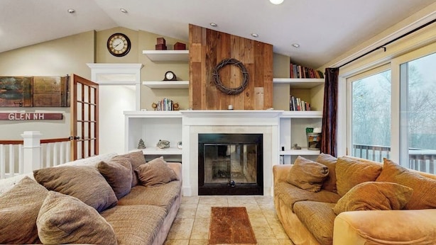 A living room with two sofas, a fireplace, bookshelves, a clock, and a window. - Serene Dog Friendly Home:  near skiing, hiking, Storyland, Shopping & dining (Glen)