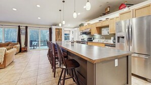 A modern kitchen with a large island, stainless steel appliances, and wooden cabinets. - Serene Dog Friendly Home:  near skiing, hiking, Storyland, Shopping & dining (Glen)