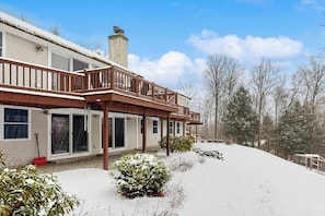 Ein zweistöckiges Haus mit einer Veranda und einem schneebedeckten Hof.