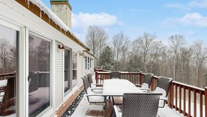 A covered outdoor deck with a table and chairs, a sliding glass door, and a wooden railing. - Serene Dog Friendly Home:  near skiing, hiking, Storyland, Shopping & dining (Glen)