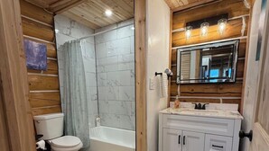 Une salle de bain aux murs lambrés, équipée de toilettes, d’une baignoire et d’un meuble-lavabo.