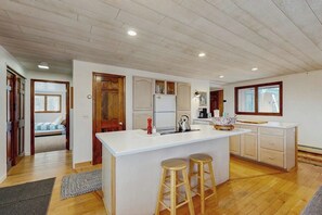 A kitchen with a central island, wooden stools, a refrigerator, and a window. - Mountainview Home w/ large yard, stunning views, close to skiing, hiking & town (Bethlehem)