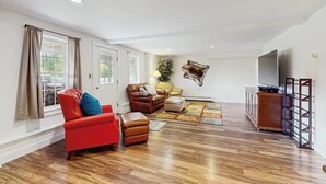 Una sala de estar con un sofá rojo, un sofá marrón, un aparador de madera y un televisor montado.