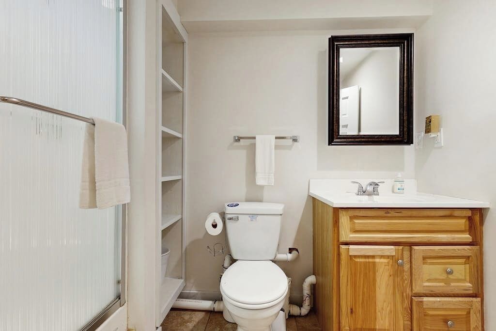 Een badkamer met toilet, wastafel, spiegel en een houten kastje.