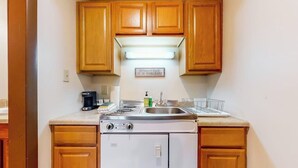 A compact kitchen with wooden cabinets, a built-in stove, and a refrigerator. - Charming and casual motel in a great location with shared resort amenities (Lincoln)