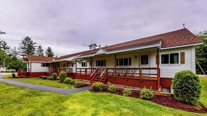 A two-story motel with a red and white exterior, a covered front porch, and a well-maintained lawn. - Charming and casual motel in a great location with shared resort amenities (Lincoln)