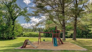 A playground with a swing set, slide, and climbing structure in a grassy park area. - Charming and casual motel in a great location with shared resort amenities (Lincoln)