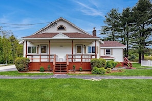 A single-story house with a front porch, a chimney, and a small front yard.