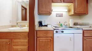 A kitchen with wooden cabinets, a stove, a sink, and a coffee maker. - Charming and casual motel in a great location with shared resort amenities (Lincoln)