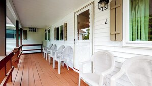 A covered porch with white plastic chairs, a wooden floor, and a white door with a number '6' on it. - Charming and casual motel in a great location with shared resort amenities (Lincoln)