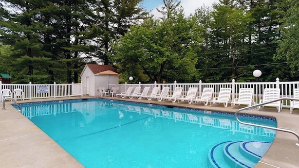 A rectangular swimming pool with a white fence and lounge chairs. - Charming and casual motel in a great location with shared resort amenities (Lincoln)